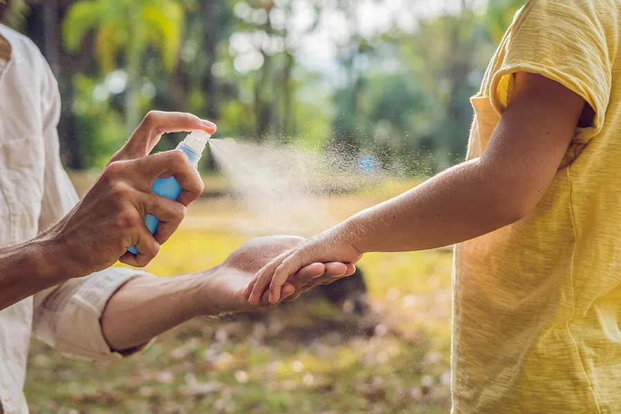 Caregiver applying insect repellent to help protect a child from mosquito‑borne illnesses